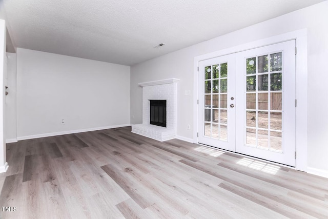 404 Shannonford Ct, Wake Forest, NC 27587 - unfurnished living room featuring french doors, wood finished floors, a textured ceiling, baseboards, and a brick fireplace