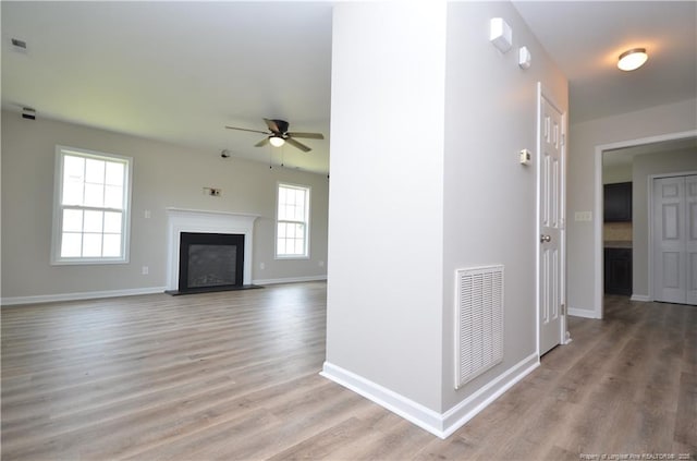 479 Broad Dr, Raeford, NC 28376 - unfurnished living room with a ceiling fan, light wood-style floors, baseboards, and a fireplace with raised hearth