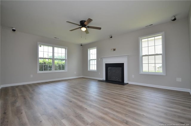479 Broad Dr, Raeford, NC 28376 - unfurnished living room with a fireplace with raised hearth, ceiling fan, wood finished floors, and baseboards