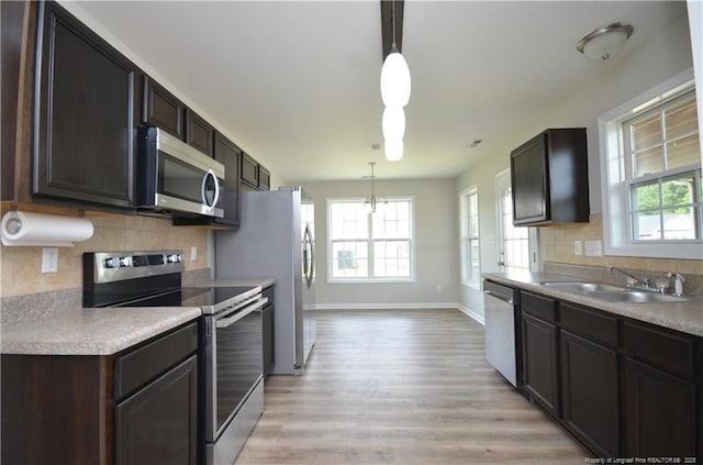 479 Broad Dr, Raeford, NC 28376 - kitchen with stainless steel appliances, a sink, light wood-style flooring, decorative backsplash, and baseboards