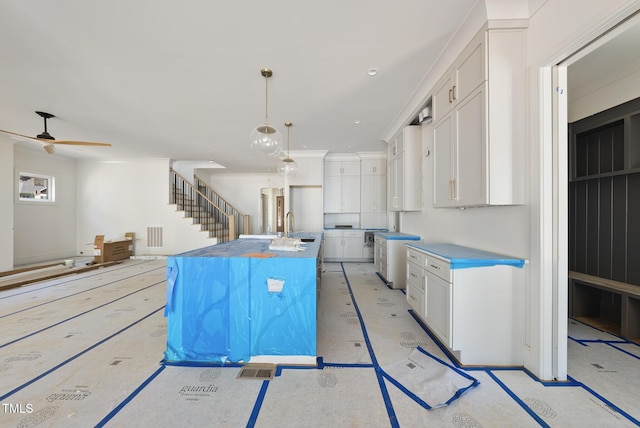1225 Dixie Trl, Raleigh, NC 27607 - kitchen with a kitchen island with sink, white cabinets, pendant lighting, and ceiling fan