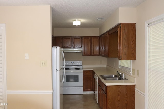 2204 Caroline Dr, Durham, NC 27705 - kitchen featuring white appliances, under cabinet range hood, light countertops, brown cabinetry, and a textured ceiling