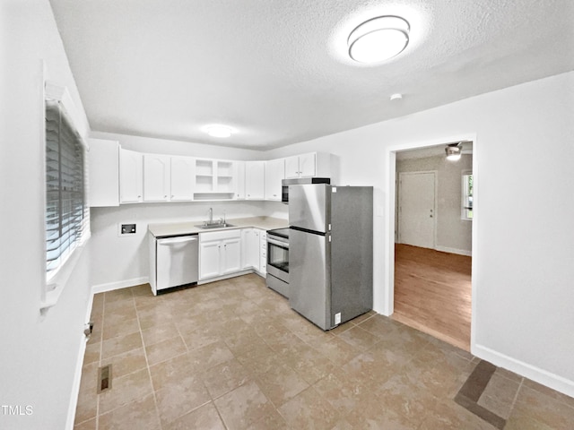 1311 Meadow Ln, Chapel Hill, NC 27516 - kitchen featuring appliances with stainless steel finishes, a sink, white cabinetry, a textured ceiling, and light tile patterned flooring