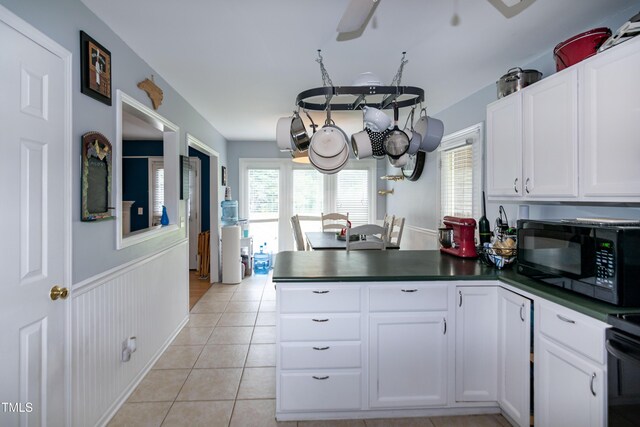 1008 Catsby Cir, Raleigh, NC 27603 - kitchen with black microwave, dark countertops, a peninsula, light tile patterned floors, and white cabinets