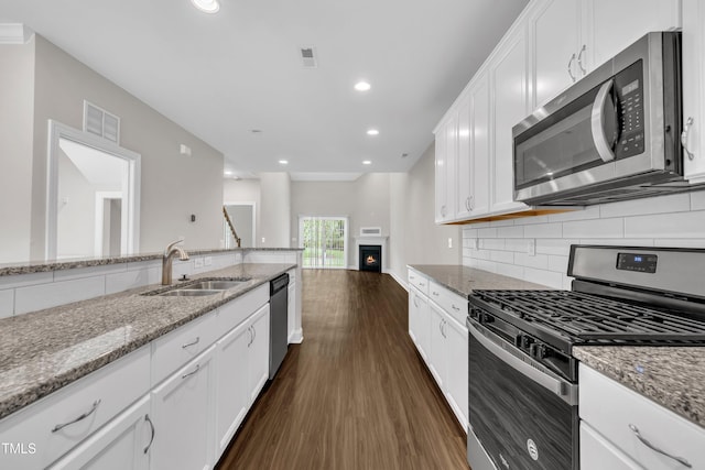 656 Barneswyck Dr, Fuquay Varina, NC 27526 - kitchen with appliances with stainless steel finishes, dark wood-type flooring, tasteful backsplash, white cabinetry, and light stone counters