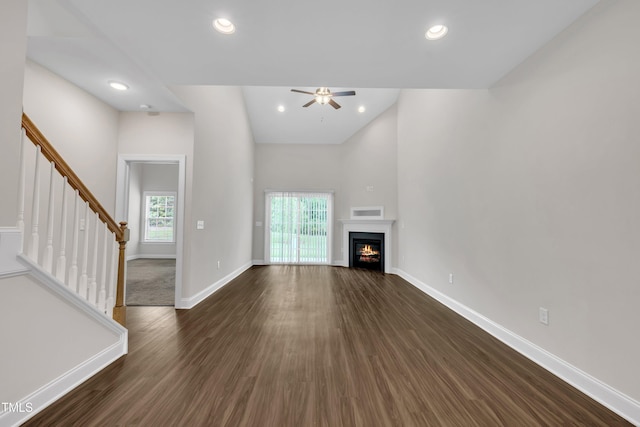 656 Barneswyck Dr, Fuquay Varina, NC 27526 - unfurnished living room featuring dark wood-style flooring, a ceiling fan, stairs, a warm lit fireplace, and recessed lighting