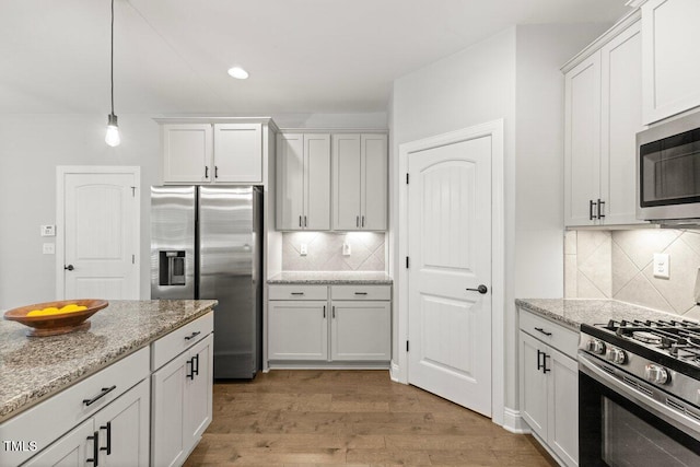 509 Holden Forest Dr, Youngsville, NC 27596 - kitchen featuring stainless steel appliances, light wood-style flooring, backsplash, white cabinetry, and light stone countertops