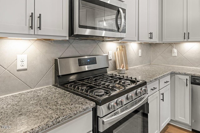 509 Holden Forest Dr, Youngsville, NC 27596 - kitchen featuring appliances with stainless steel finishes, decorative backsplash, light stone counters, and white cabinets