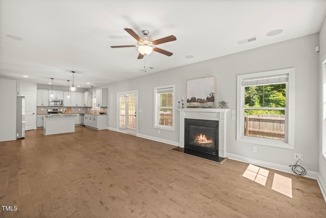 509 Holden Forest Dr, Youngsville, NC 27596 - unfurnished living room featuring a glass covered fireplace, healthy amount of natural light, ceiling fan, wood finished floors, and recessed lighting