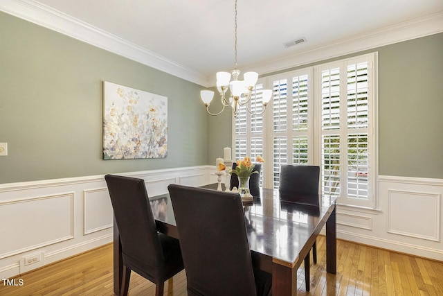 2311 Woodwyck Way, Raleigh, NC 27604 - dining room featuring a chandelier, a decorative wall, crown molding, light wood-style floors, and a wainscoted wall