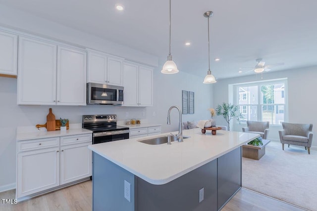 1359 Chowan Ave, Durham, NC 27713 - kitchen with appliances with stainless steel finishes, white cabinets, light countertops, a kitchen island with sink, and recessed lighting