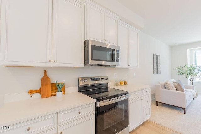 1359 Chowan Ave, Durham, NC 27713 - kitchen featuring appliances with stainless steel finishes, open floor plan, white cabinets, and light countertops
