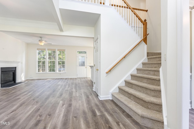 1613 Patterson Grove Rd, Apex, NC 27502 - unfurnished living room with stairs, wood finished floors, a ceiling fan, beam ceiling, and a glass covered fireplace