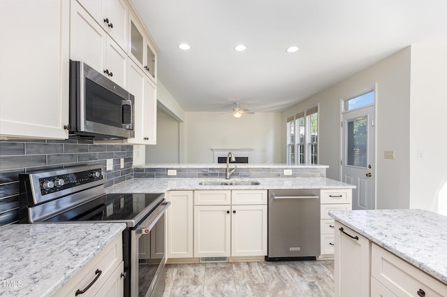 1613 Patterson Grove Rd, Apex, NC 27502 - kitchen featuring appliances with stainless steel finishes, a sink, ceiling fan, a peninsula, and decorative backsplash
