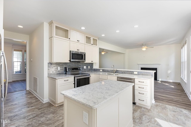 1613 Patterson Grove Rd, Apex, NC 27502 - kitchen featuring appliances with stainless steel finishes, a ceiling fan, a peninsula, a sink, and decorative backsplash