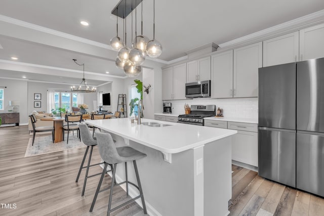 1729 Starlit Sky Ln, Cary, NC 27519 - kitchen featuring stainless steel appliances, open floor plan, ornamental molding, a chandelier, and light wood-type flooring