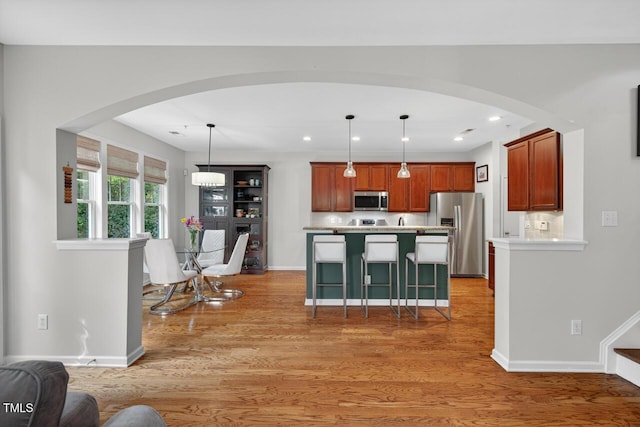 117 Sonoma Way, Chapel Hill, NC 27516 - kitchen featuring stainless steel appliances, light countertops, light wood-style flooring, arched walkways, and a kitchen bar