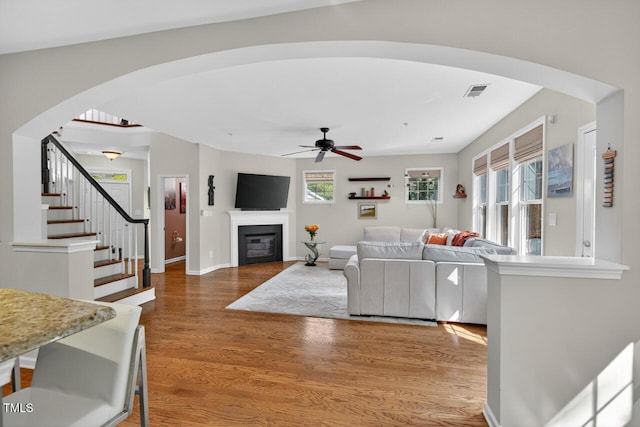 117 Sonoma Way, Chapel Hill, NC 27516 - living area featuring wood finished floors, a ceiling fan, arched walkways, a glass covered fireplace, and stairs