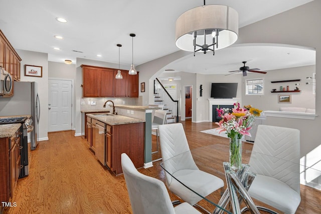117 Sonoma Way, Chapel Hill, NC 27516 - kitchen with arched walkways, brown cabinetry, appliances with stainless steel finishes, light wood-type flooring, and a ceiling fan