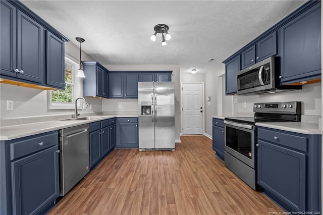 107 Beaumont Ct, Raeford, NC 28376 - kitchen with stainless steel appliances, a sink, blue cabinets, light wood-style flooring, and a textured ceiling