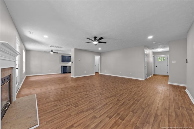 107 Beaumont Ct, Raeford, NC 28376 - unfurnished living room featuring a ceiling fan, a fireplace with flush hearth, wood finished floors, baseboards, and recessed lighting