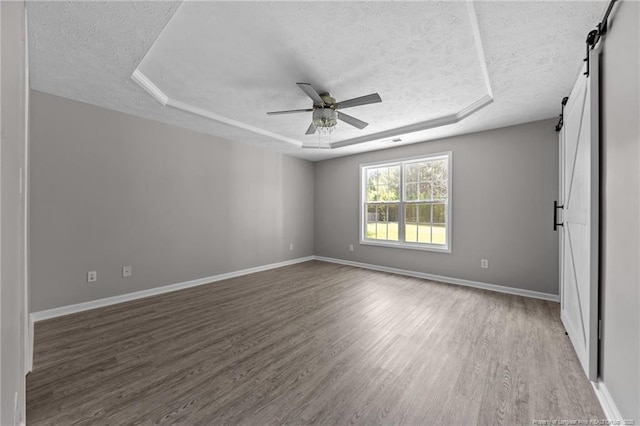 107 Beaumont Ct, Raeford, NC 28376 - empty room with a barn door, a textured ceiling, wood finished floors, a ceiling fan, and baseboards