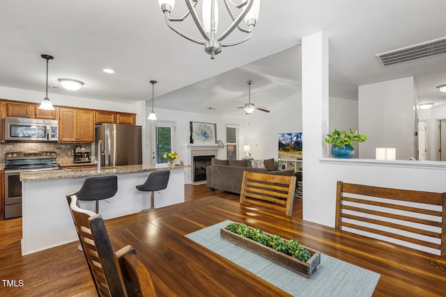 131 Abacos Ct, Clayton, NC 27520 - dining room with dark wood-type flooring, a fireplace, ceiling fan, a chandelier, and vaulted ceiling