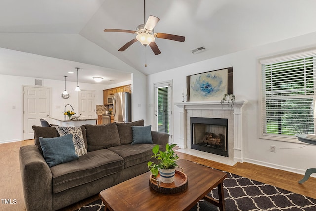 131 Abacos Ct, Clayton, NC 27520 - living area with vaulted ceiling, light wood-style flooring, a tile fireplace, ceiling fan, and plenty of natural light