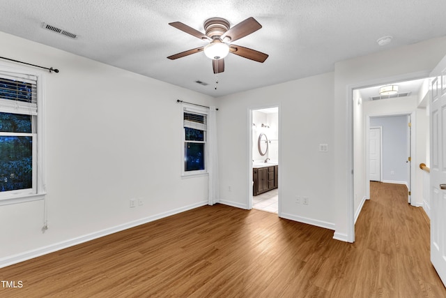 8 Great Oak Ct, Durham, NC 27713 - unfurnished bedroom with light wood-type flooring, a textured ceiling, connected bathroom, and ceiling fan