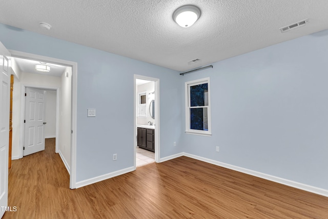 8 Great Oak Ct, Durham, NC 27713 - unfurnished bedroom with light wood finished floors, a textured ceiling, and ensuite bathroom