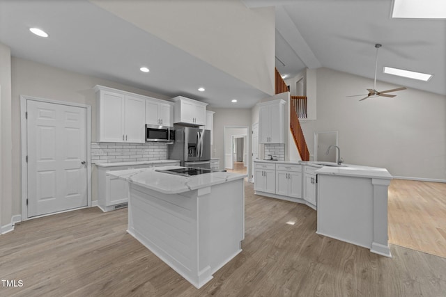 6008 Chittim Ct, Raleigh, NC 27616 - kitchen with appliances with stainless steel finishes, a peninsula, tasteful backsplash, white cabinetry, and lofted ceiling