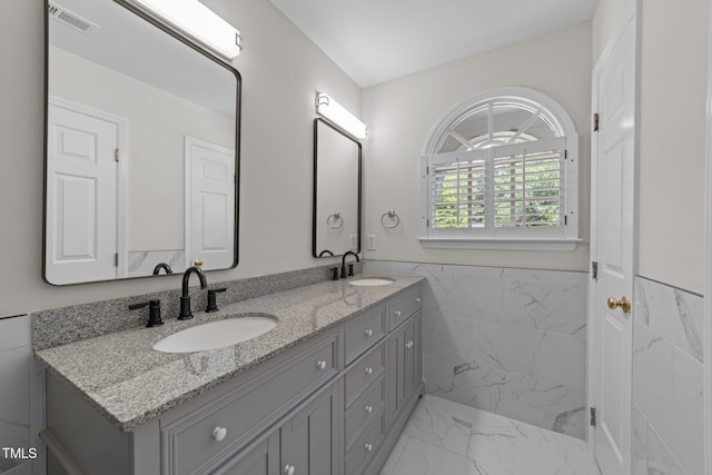 6008 Chittim Ct, Raleigh, NC 27616 - bathroom featuring marble look tiles, double vanity, a wainscoted wall, and tile walls