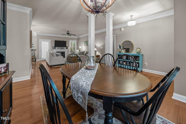 45 Chaucer Ct W, Zebulon, NC 27597 - dining room with a fireplace, ceiling fan, wood finished floors, decorative columns, and baseboards