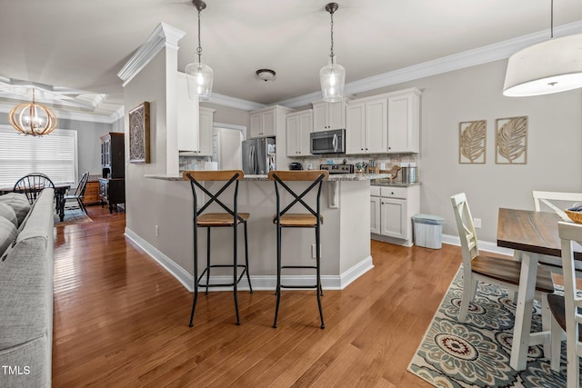 45 Chaucer Ct W, Zebulon, NC 27597 - kitchen with appliances with stainless steel finishes, a chandelier, a breakfast bar, white cabinets, and ornamental molding