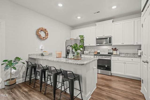 947 Weatherby Ln, Creedmoor, NC 27522 - kitchen featuring stainless steel appliances, a kitchen bar, white cabinets, dark wood-style flooring, and recessed lighting