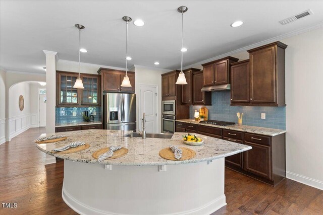 1705 Bodwin Ln, Apex, NC 27502 - kitchen featuring stainless steel appliances, under cabinet range hood, dark brown cabinetry, decorative backsplash, and a kitchen island with sink