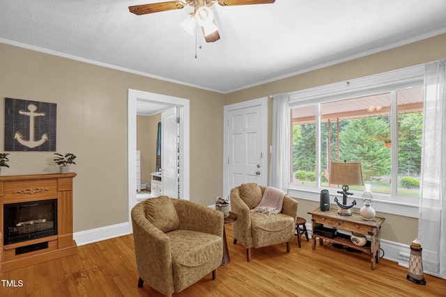 3315 Mebane Oaks Rd, Mebane, NC 27302 - living area with light wood-type flooring, ceiling fan, ornamental molding, baseboards, and a fireplace with raised hearth