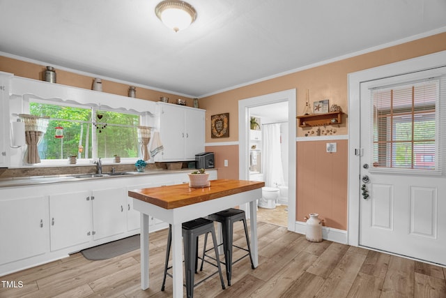 3315 Mebane Oaks Rd, Mebane, NC 27302 - kitchen featuring a sink, white cabinets, light wood-type flooring, ornamental molding, and wainscoting