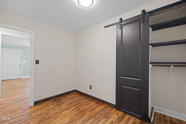 105 Hanna St, Carrboro, NC 27510 - unfurnished bedroom featuring a barn door, wood finished floors, and a closet