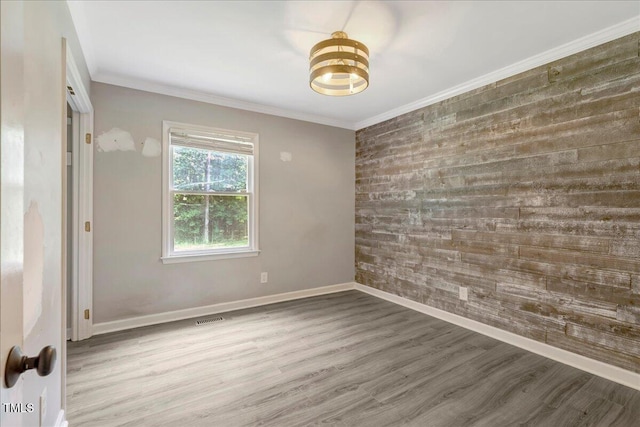 224 Oakcrest Dr, Wake Forest, NC 27587 - empty room with wood finished floors, an accent wall, baseboards, wooden walls, and crown molding