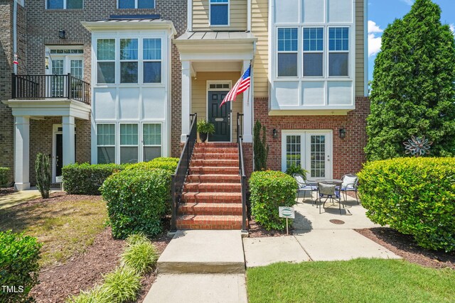 9141 Falkwood Rd, Raleigh, NC 27617 - doorway to property featuring brick siding, a standing seam roof, and a patio