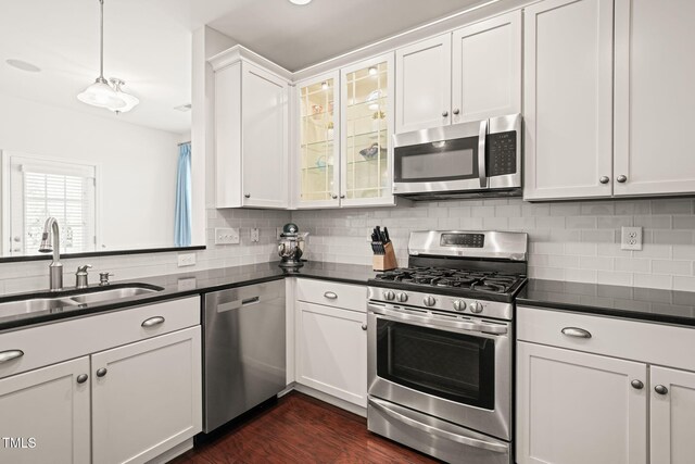 9141 Falkwood Rd, Raleigh, NC 27617 - kitchen with appliances with stainless steel finishes, dark countertops, tasteful backsplash, white cabinetry, and glass insert cabinets