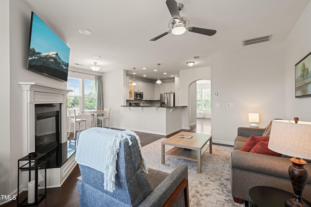 9141 Falkwood Rd, Raleigh, NC 27617 - living room with ceiling fan, healthy amount of natural light, arched walkways, wood finished floors, and recessed lighting
