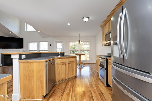 25 Ruth Cir, Fuquay Varina, NC 27526 - kitchen featuring appliances with stainless steel finishes, light wood finished floors, a chandelier, a fireplace, and an island with sink