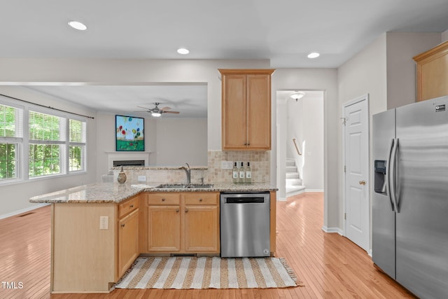 4804 Carmen Ln, Durham, NC 27707 - kitchen featuring appliances with stainless steel finishes, a ceiling fan, light wood-style flooring, light brown cabinetry, and a fireplace