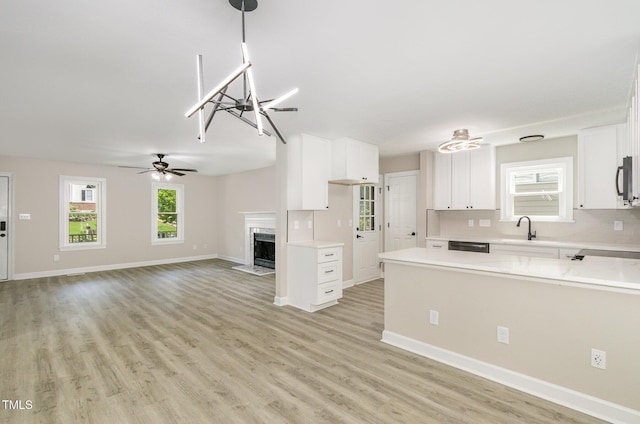 2324 Dahlgreen Rd, Raleigh, NC 27615 - kitchen featuring light countertops, white cabinetry, a ceiling fan, a high end fireplace, and light wood-type flooring