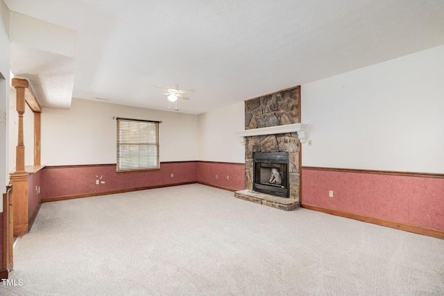2817 Henslowe Dr, Raleigh, NC 27603 - unfurnished living room with carpet flooring, a ceiling fan, a stone fireplace, a wainscoted wall, and ornate columns