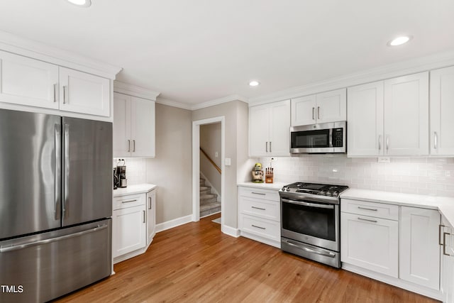 433 Rosehaven Dr, Raleigh, NC 27609 - kitchen with appliances with stainless steel finishes, crown molding, light countertops, white cabinetry, and light wood-style flooring