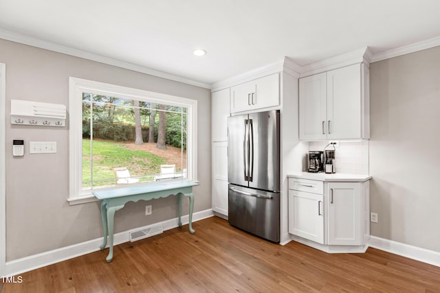 433 Rosehaven Dr, Raleigh, NC 27609 - kitchen featuring freestanding refrigerator, ornamental molding, light wood-type flooring, white cabinetry, and backsplash