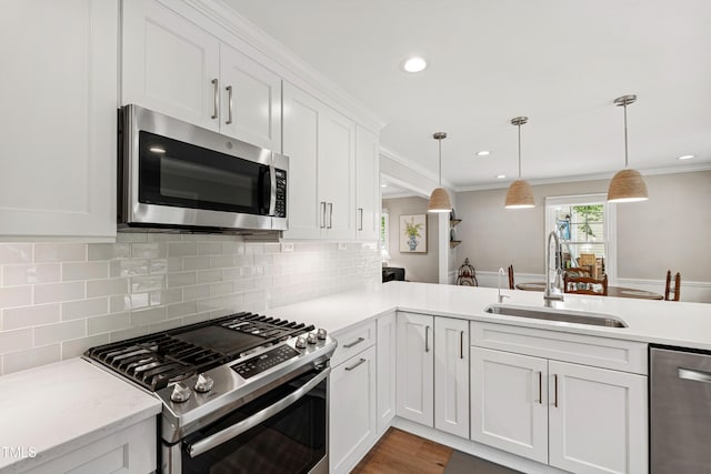 433 Rosehaven Dr, Raleigh, NC 27609 - kitchen featuring appliances with stainless steel finishes, white cabinets, crown molding, tasteful backsplash, and hanging light fixtures